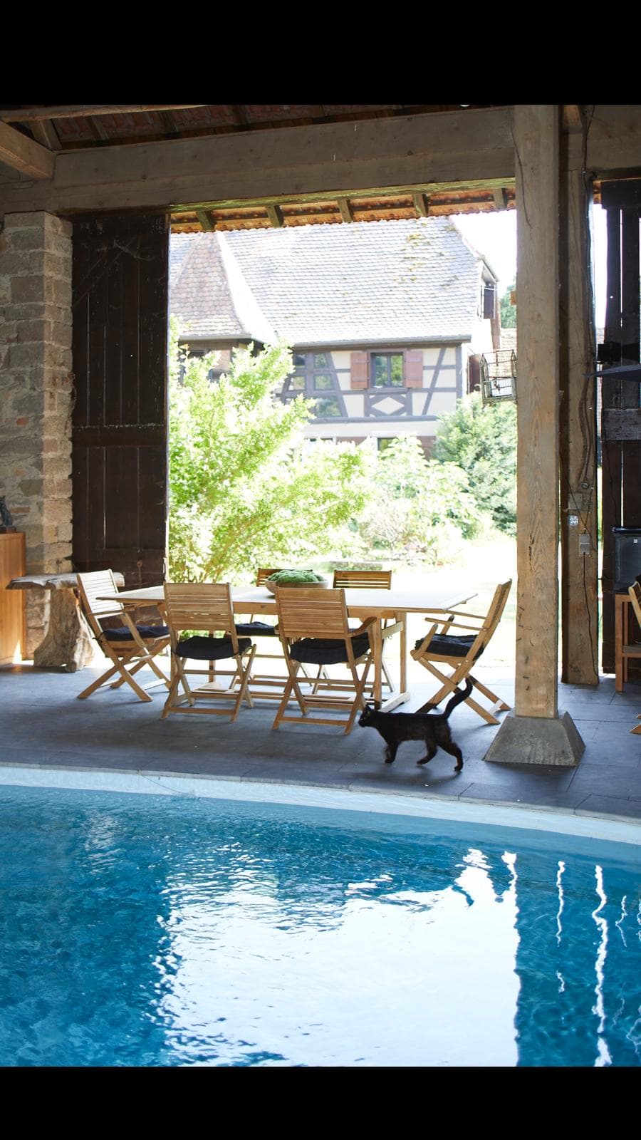 Terrasse couverte avec table en bois et vue sur maison alsacienne