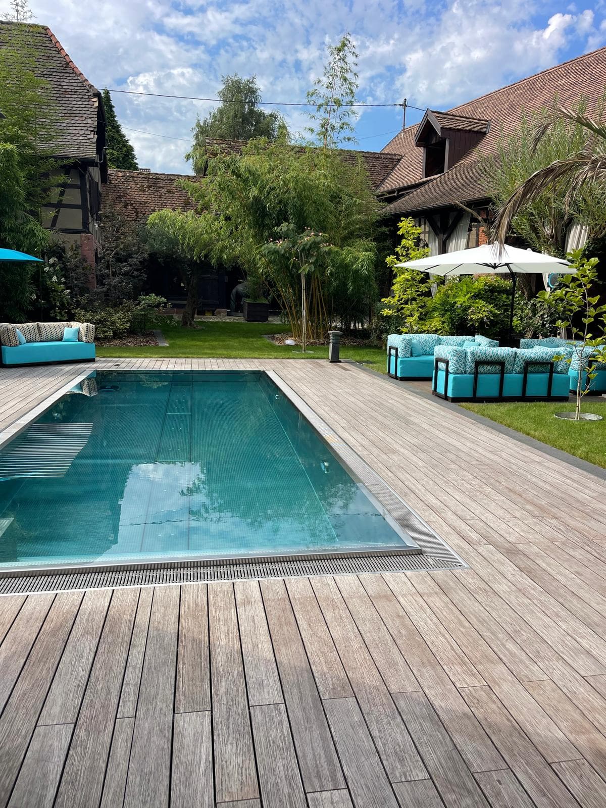 Piscine extérieure et canapés outdoor face à une maison alsacienne