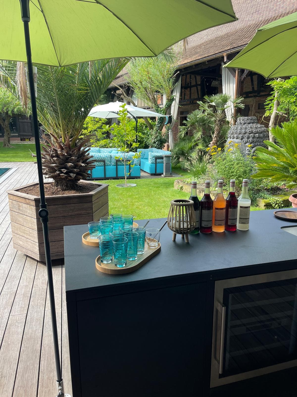 Bar de jardin avec verres turquoise sous parasol vert