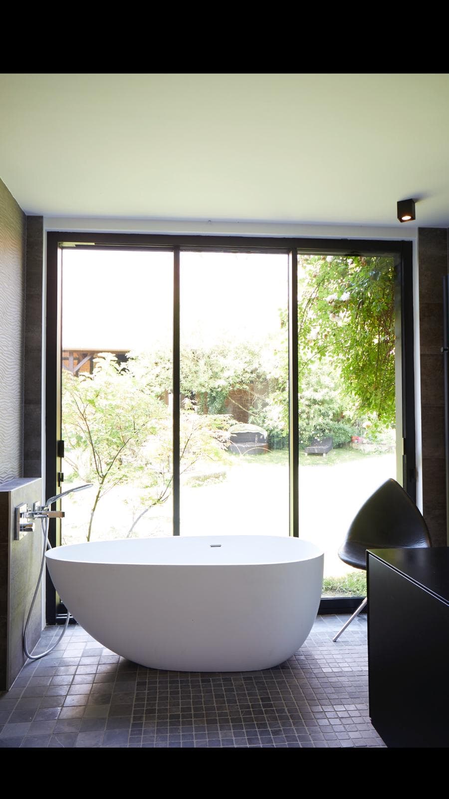Salle de bain minimaliste avec baignoire îlot face à une baie vitrée